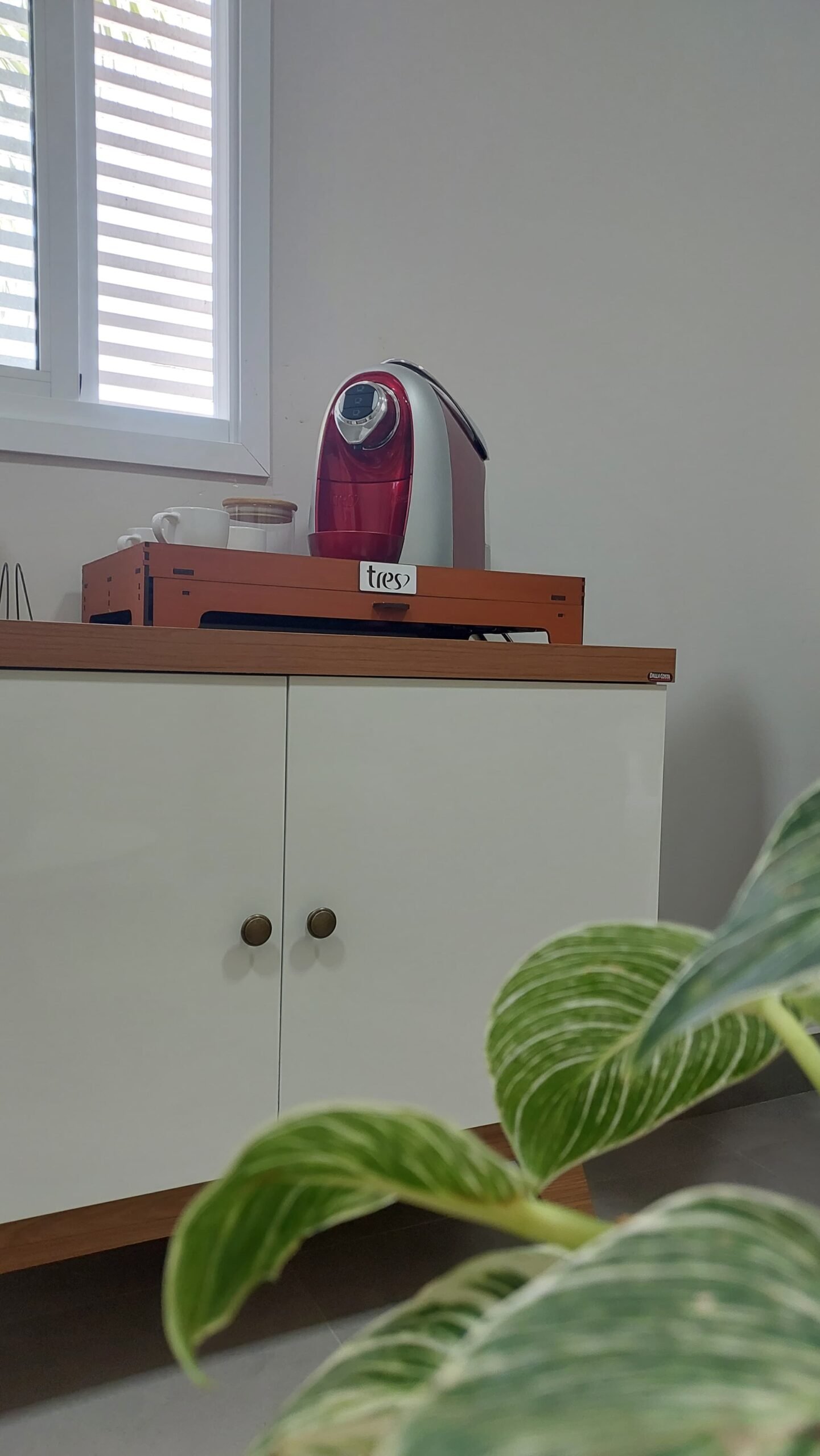 Detalhe da sala de atendimento, com aparador e, sobre ele, cafeteira elétrica para servir os pacientes